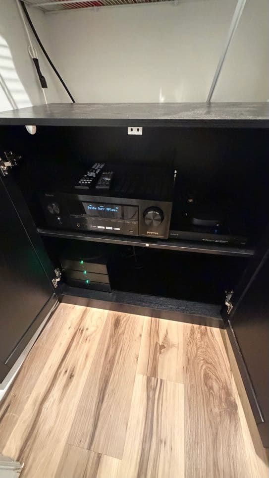 Surround-sound AV receiver installed in a black cabinet with the display reading Dolby Surround