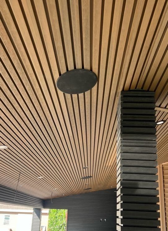 Flush in-ceiling round speaker installed in a wood-slat patio ceiling